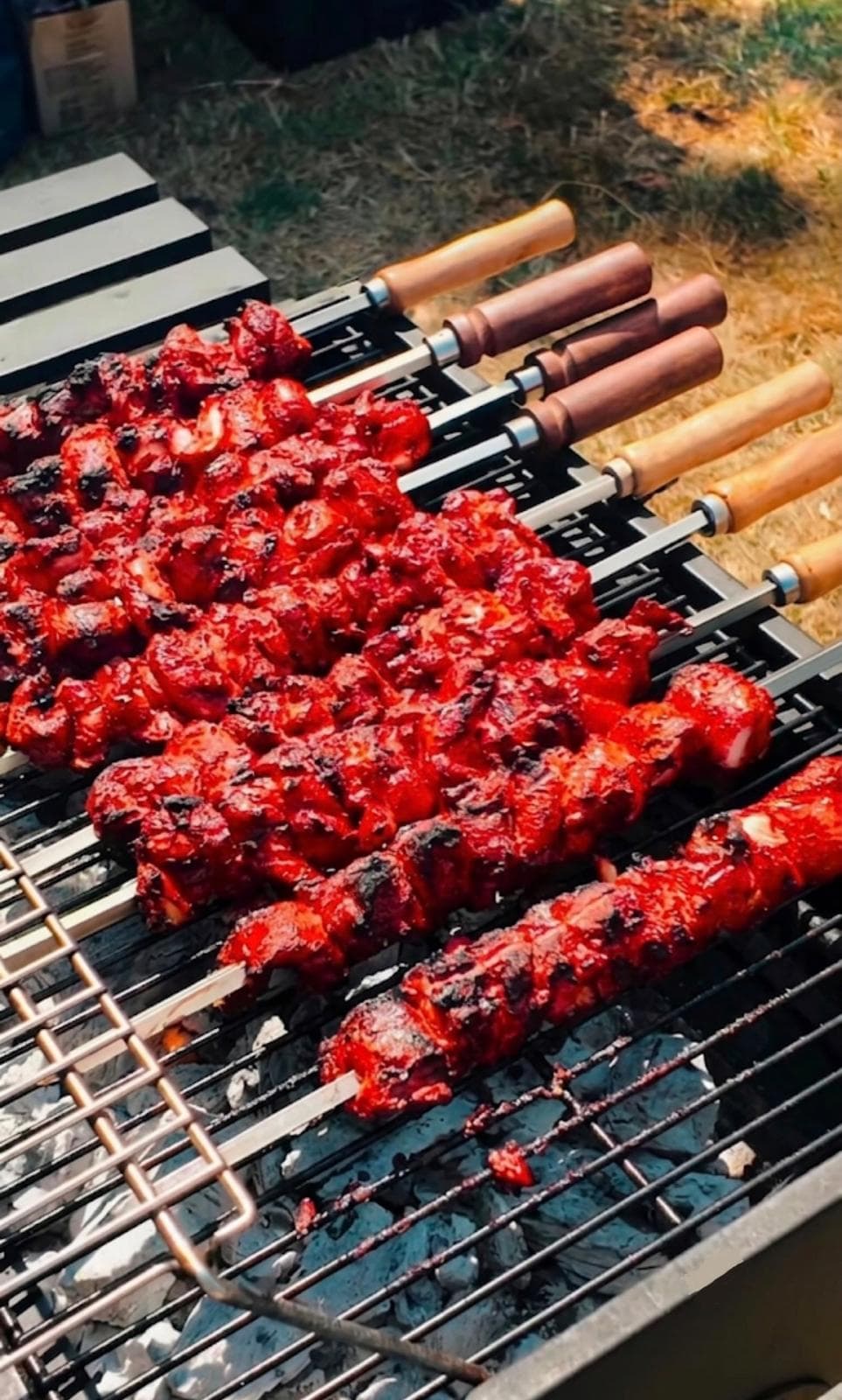 Rows of red-marinated chicken mishkaki skewers charring over open coals on the stall's grill.
